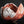 Load image into Gallery viewer, A handmade ceramic bowl with a textured, organic shape, featuring a reddish-brown clay body and white glaze splatters, set against a solid black background.
