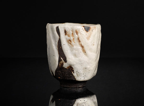 Ceramic cup with brown and white glaze on a black background