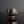 Load image into Gallery viewer, A small handmade ceramic cup with a textured, rustic finish in dark brown and black tones, set against a dark gray background with a soft reflection below.
