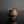 Load image into Gallery viewer, A small handmade ceramic cup with a textured, rustic finish in dark brown and black tones, set against a dark gray background with a soft reflection below.
