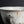 將圖片載入到圖庫檢視器中， A close-up of a ceramic bowl with a textured off-white glaze, featuring a crackled finish, small brown specks, and a dark gray painted area on the front, set against a dark background.

