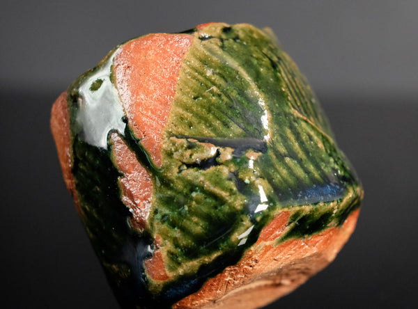 Close-up of a ceramic cup with multicolored glaze on a black background