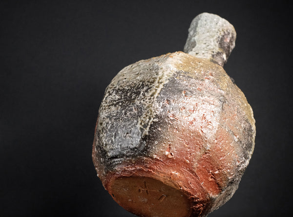 Ancient ceramic pot with a dark brown and black exterior on a black background