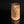 Load image into Gallery viewer, A handmade ceramic vase with a textured, rustic finish in earthy terracotta and brown tones, standing on a reflective black surface against a black background.
