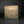 Load image into Gallery viewer, A rectangular metal box with a textured, metallic bronze finish, shown from a three-quarters perspective against a dark studio background.
