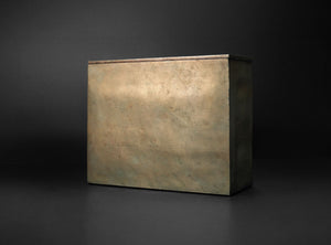 A rectangular metal box with a textured, metallic bronze finish, shown from a three-quarters perspective against a dark studio background.