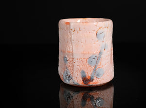 Cylindrical ceramic cup with textured surface on a black background