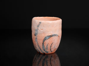 Small ceramic cup with marbled design on a black background