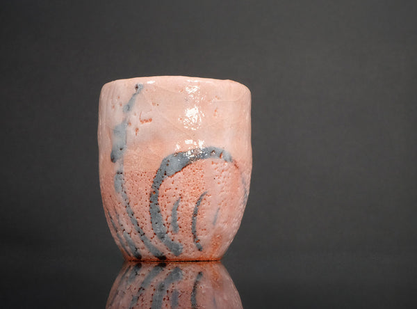 Ceramic cup with pink and blue abstract design on a dark background