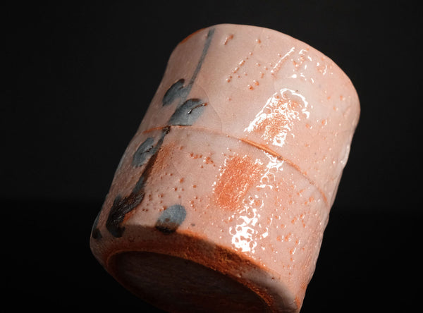 Cylindrical ceramic object with a textured surface on a black background