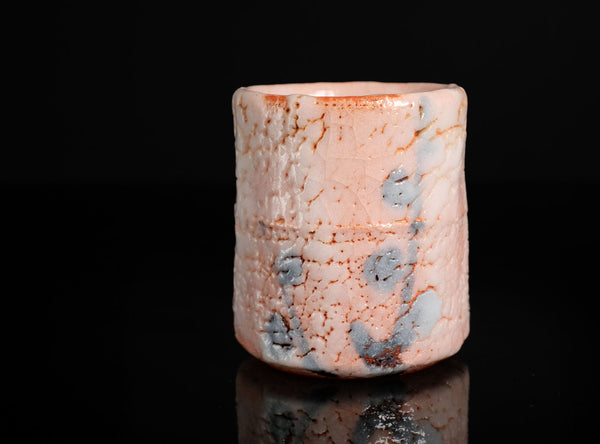 Cylindrical ceramic cupwith a textured surface on a black background