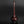Load image into Gallery viewer, A glossy dark reddish-brown ceramic vase with a long, slender neck and a rounded base, displayed on a reflective black surface against a dark gray background.
