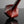 Load image into Gallery viewer, A close-up studio shot of a glossy, faceted sculptural object in a deep reddish-brown color, resting on a reflective dark surface against a neutral gray background.
