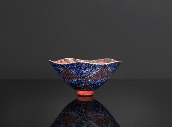 Ceramic bowl with a unique glaze pattern on a reflective black surface