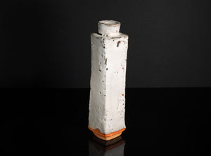 Square ceramic vase with textured surface on a black background