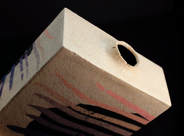 Close-up of a textured rectangular object with a hole on a black background