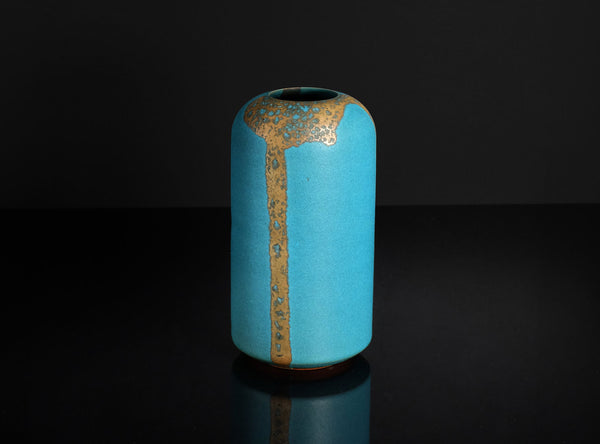 Blue ceramic vase with gold accents on a black background