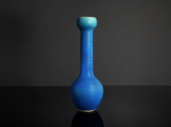 Blue ceramic vase on a dark surface with a dark background