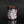 Load image into Gallery viewer, A handmade ceramic cup with a textured, organic surface featuring a mix of white, pink, gray, and dark brown glazes, set against a dark reflective background.
