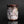 Load image into Gallery viewer, A handmade ceramic cup with a textured, organic surface featuring a mix of white, pink, gray, and dark brown glazes, set against a dark reflective background.
