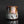 Load image into Gallery viewer, A handmade ceramic cup with a dripping glaze finish, featuring a mix of brown, gold, pink, and gray colors, set against a dark reflective background.
