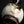 Load image into Gallery viewer, A close-up of a ceramic vase with a rounded, bulbous body covered in thick, textured off-white glaze, dark brown base, and glossy black handle, set against a solid black background.
