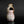 Load image into Gallery viewer, A small handmade ceramic vase with a unique organic shape, featuring a pink and white glaze with brown and gold accents, set against a dark gray background with a reflective black surface.
