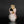 Load image into Gallery viewer, A small handmade ceramic vase with a unique organic shape, featuring a pink and white glaze with brown and gold accents, set against a dark gray background with a reflective black surface.
