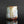 Load image into Gallery viewer, A handmade ceramic cup with a textured, organic shape and a dripping glaze in pale blue, cream, and brown, set against a dark gray background with a soft reflection below.
