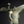 Load image into Gallery viewer, An ancient bronze ritual vessel with a weathered green patina, featuring a curved handle and a decorative emblem on the body, set against a dark background.
