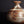 Load image into Gallery viewer, A close-up of a handmade ceramic bottle with a rounded body, narrow neck, and flared rim, featuring a textured glaze in earthy brown, white, and black marbled patterns against a dark background.

