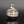Load image into Gallery viewer, A small round ceramic vase with a narrow neck, featuring a marbled glaze of brown, white, and gray, displayed on a reflective black surface against a dark gray background.
