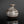 Load image into Gallery viewer, A small round ceramic vase with a narrow neck and flared rim, featuring horizontal bands of glossy brown, gray, and white glaze, set against a dark reflective background.

