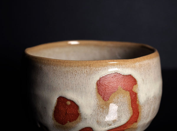 Ceramic bowl with red and brown speckles on a dark background