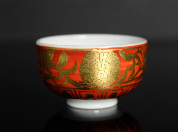 Decorative cup with red and gold design on a black background