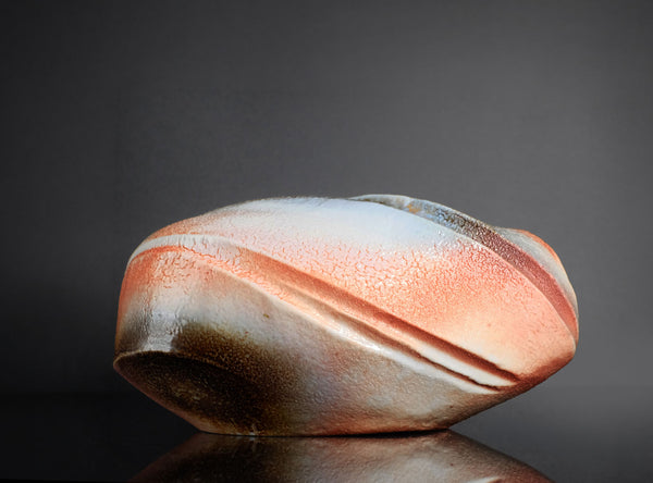 Decorative vase with striped pattern on a reflective surface