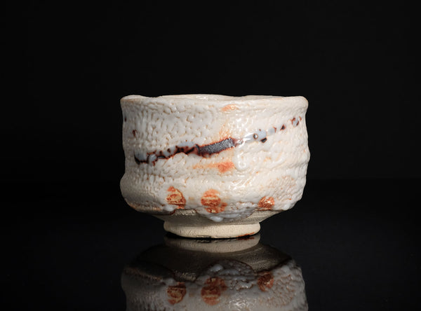 Ceramic bowl with textured surface and red and black patterns on a black background