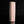 Load image into Gallery viewer, A tall, cylindrical ceramic vase with a textured, crackled surface in a pale peach-pink color, standing upright on a reflective black surface against a solid black background.
