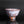 Load image into Gallery viewer, A handmade ceramic tea bowl with a textured, speckled glaze in earthy brown, white, and muted pink tones, shown on a reflective black surface against a dark gray background.
