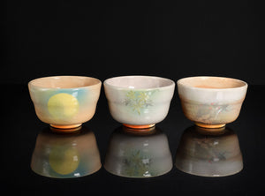 Three ceramic cups with floral patterns on a black background