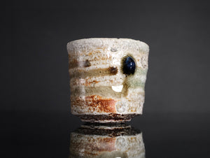 Ceramic cup with a dark spot on a reflective surface against a black background