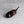 Load image into Gallery viewer, A glossy dark purple eggplant-shaped object with a long stem, photographed on a light gray textured surface.
