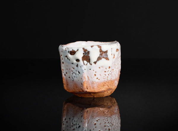 Ceramic cup with unique glaze pattern on a black background