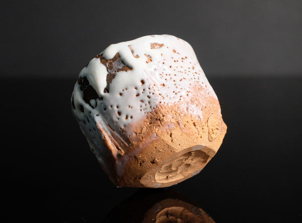 Ceramic dice with white top and brown sides on a black background