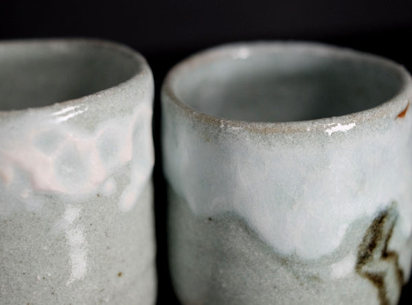 Two ceramic cups with a textured surface on a dark background