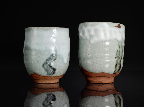 Two ceramic cups with a textured surface on a black background
