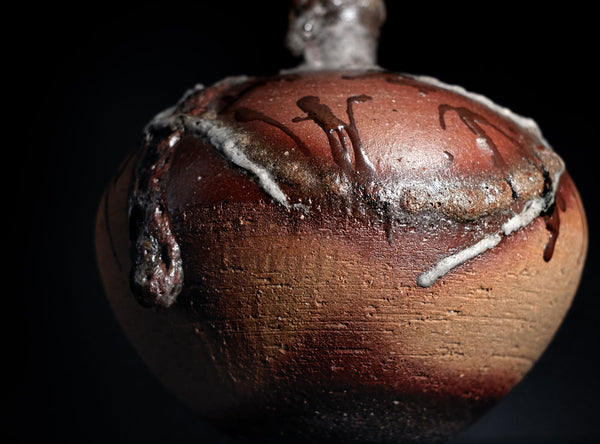Close-up of a brown ceramic object with white accents on a black background