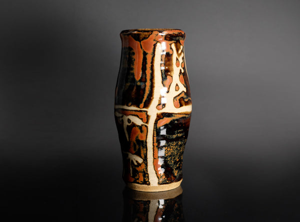 Ceramic vase with brown and beige glaze on a dark gray background