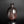 Load image into Gallery viewer, A small ceramic vase with a narrow neck and rounded body, featuring a metallic bronze to dark brown glaze with a subtle vertical seam, set against a dark gray gradient background with a soft reflection below.
