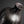 Load image into Gallery viewer, A close-up studio shot of a dark ceramic vase with a textured, matte finish and a flared neck, set against a dark gray background.
